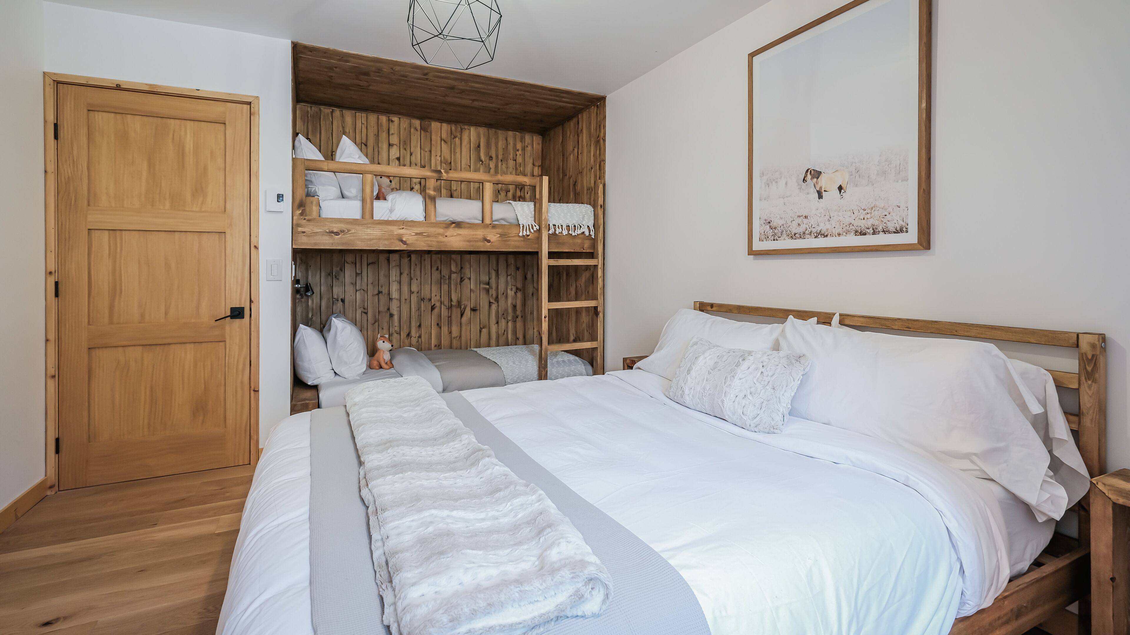 Une chambre avec un lit superposé, une armoire en bois et un tableau encadré accroché au mur.