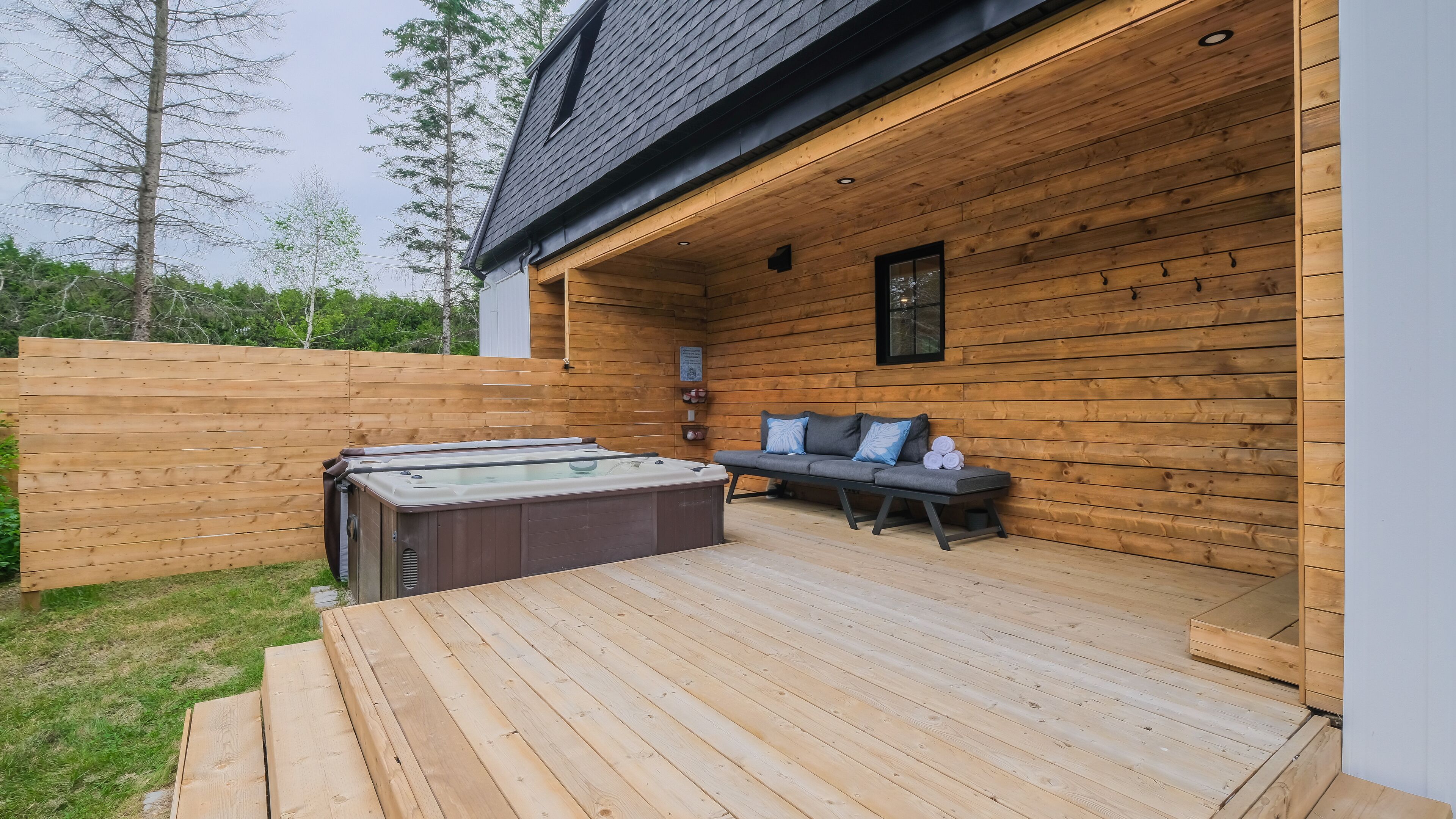 A wooden deck with a hot tub and a sofa with cushions.