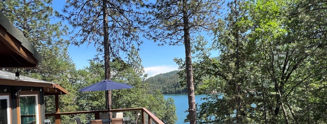 Eine Holzterrasse mit Sitzgelegenheiten und Blick auf einen See.