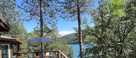 Una terraza de madera con asientos exteriores y vistas a un lago.