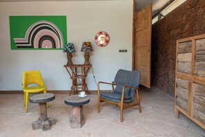 Une pièce avec un sol en pierre, une chaise en bois, une chaise jaune et une table sur laquelle se trouve une tasse.