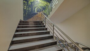 Una escalera con barandilla de metal y un mural con un bosque en la pared superior.