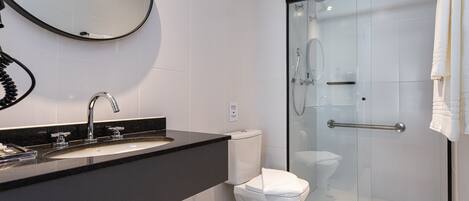 Un baño moderno con lavamanos de superficie negra, inodoro blanco y zona de ducha con mampara de vidrio.