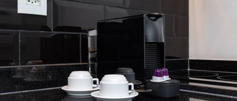 A modern kitchen with black countertops, a coffee machine, and a set of white cups and saucers.