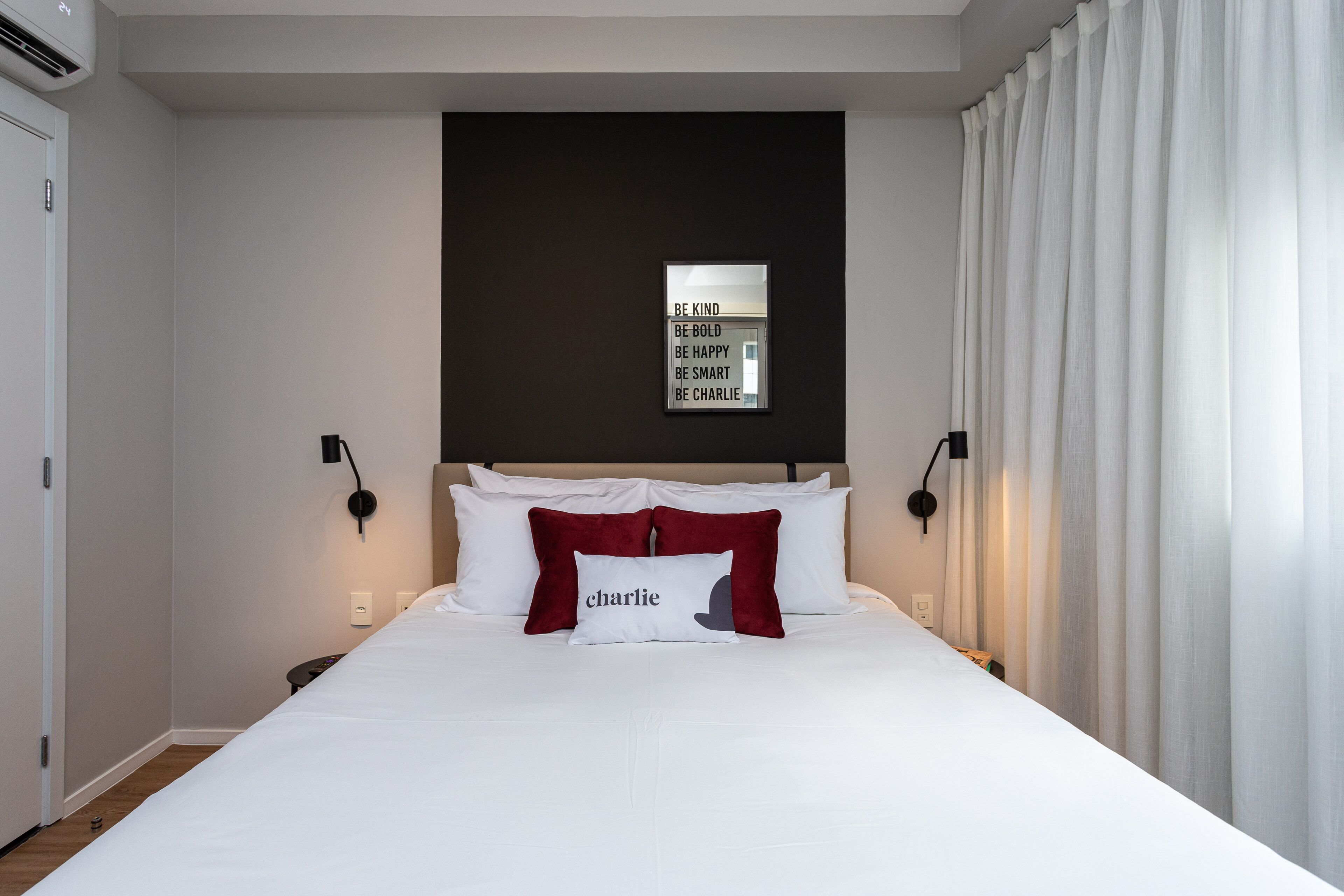 Una cama bien hecha con ropa blanca y una almohada que dice "charlie".