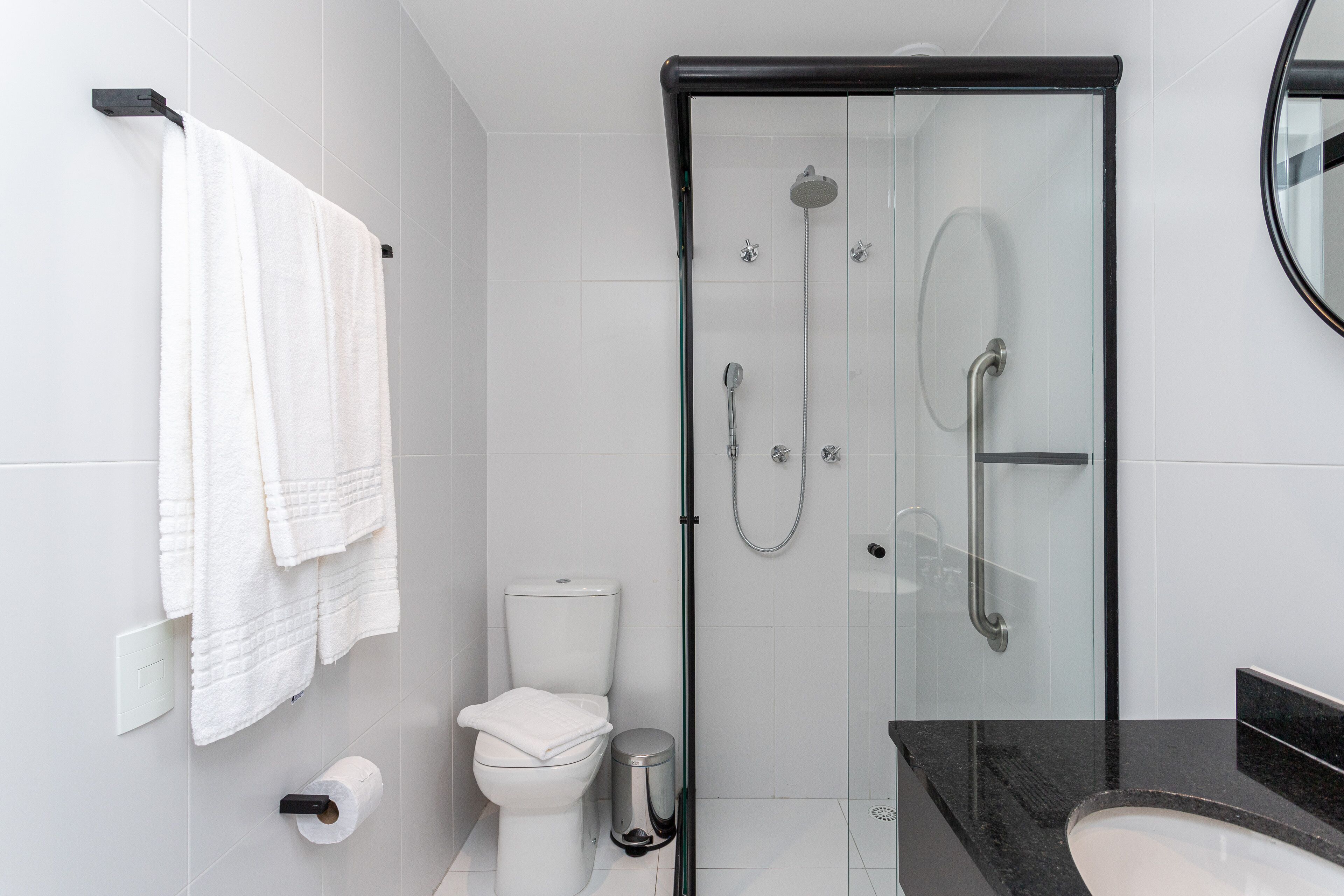 A modern bathroom with a glass-enclosed shower, a toilet, and a sink.