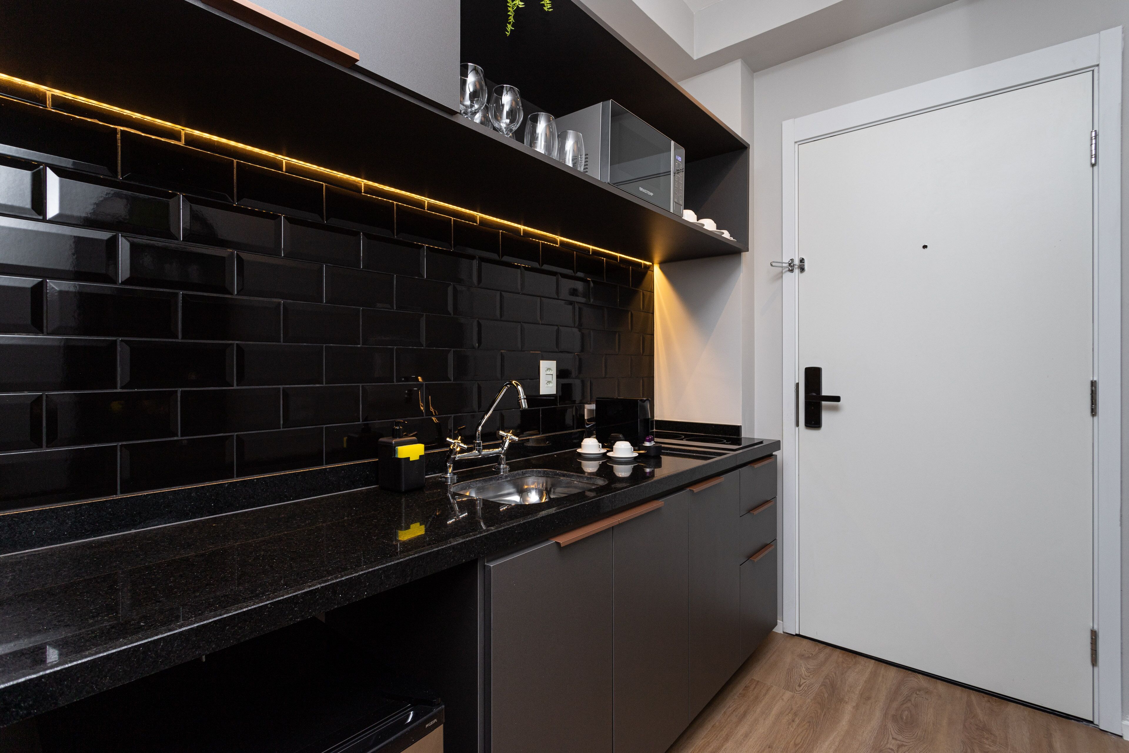 A modern kitchen with black countertops, a built-in oven, and a white door.