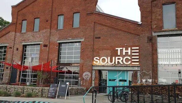 A brick building with large windows and a sign that reads "THE SOURCE".