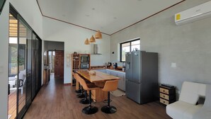 Uma cozinha moderna com uma ilha central, banquetas, geladeira e área de refeições.