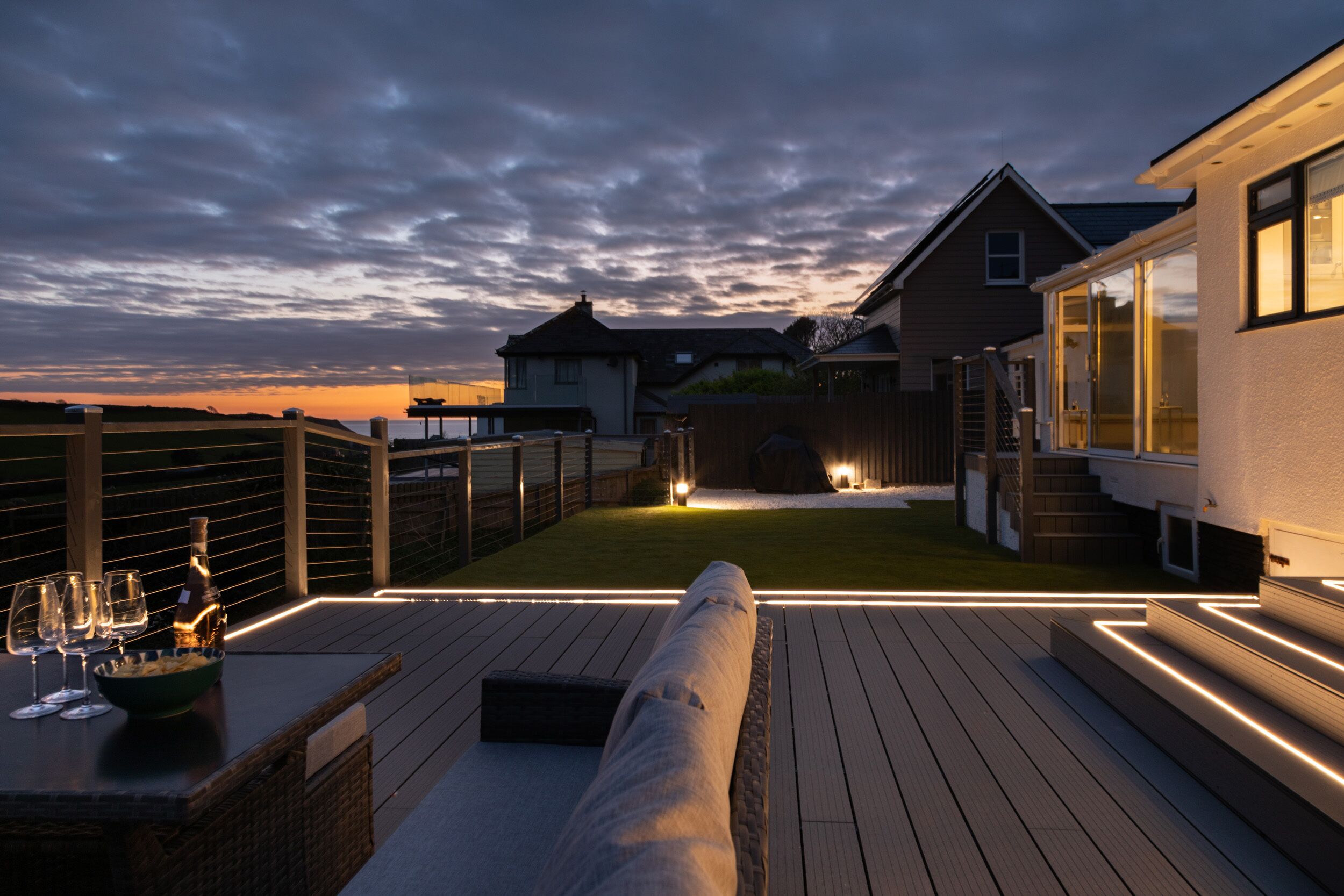 Une terrasse dotée d’un espace détente, d’une piscine et offrant une vue sur les maisons au loin.