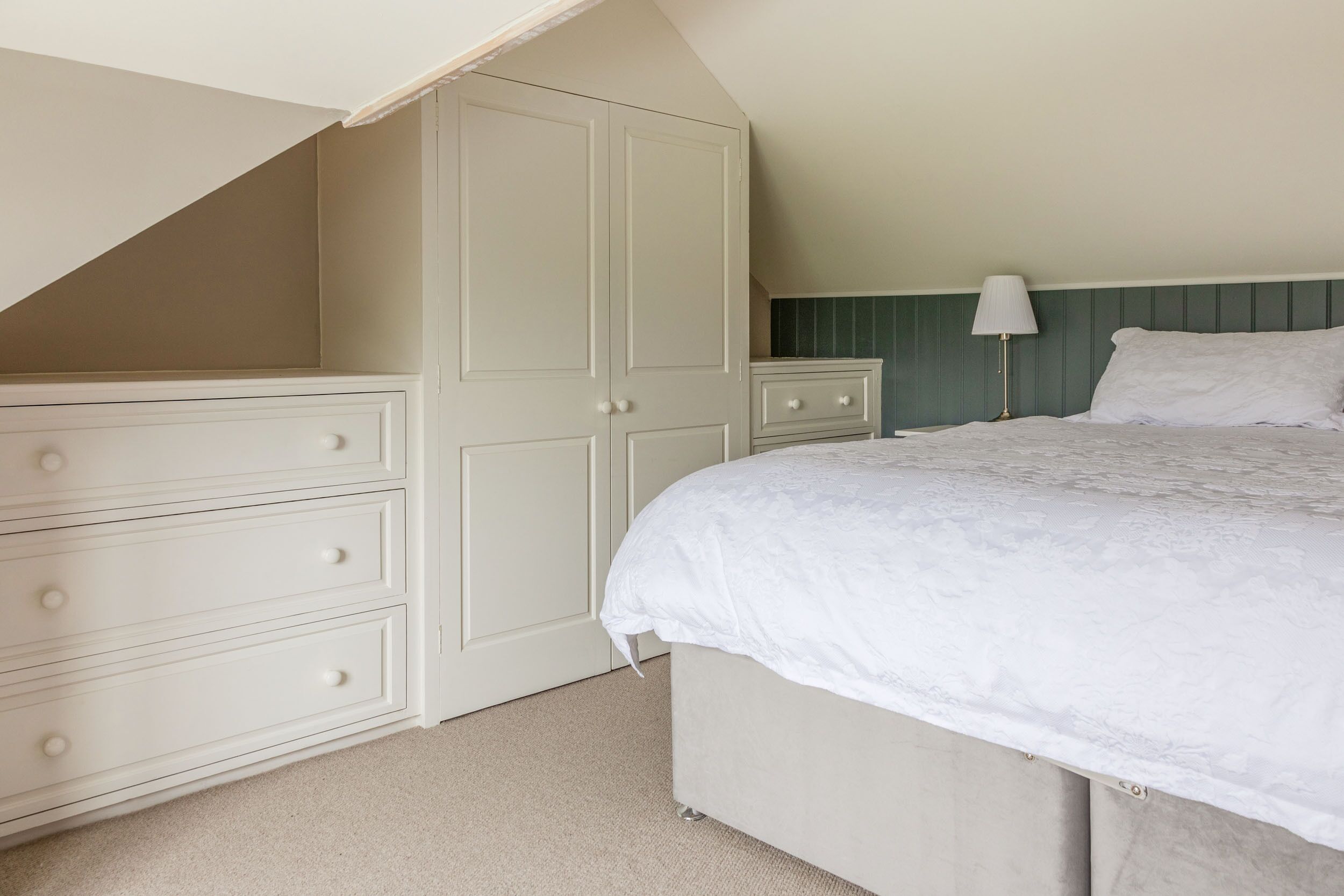 A bedroom with a bed, a nightstand, a dresser, and a wardrobe.