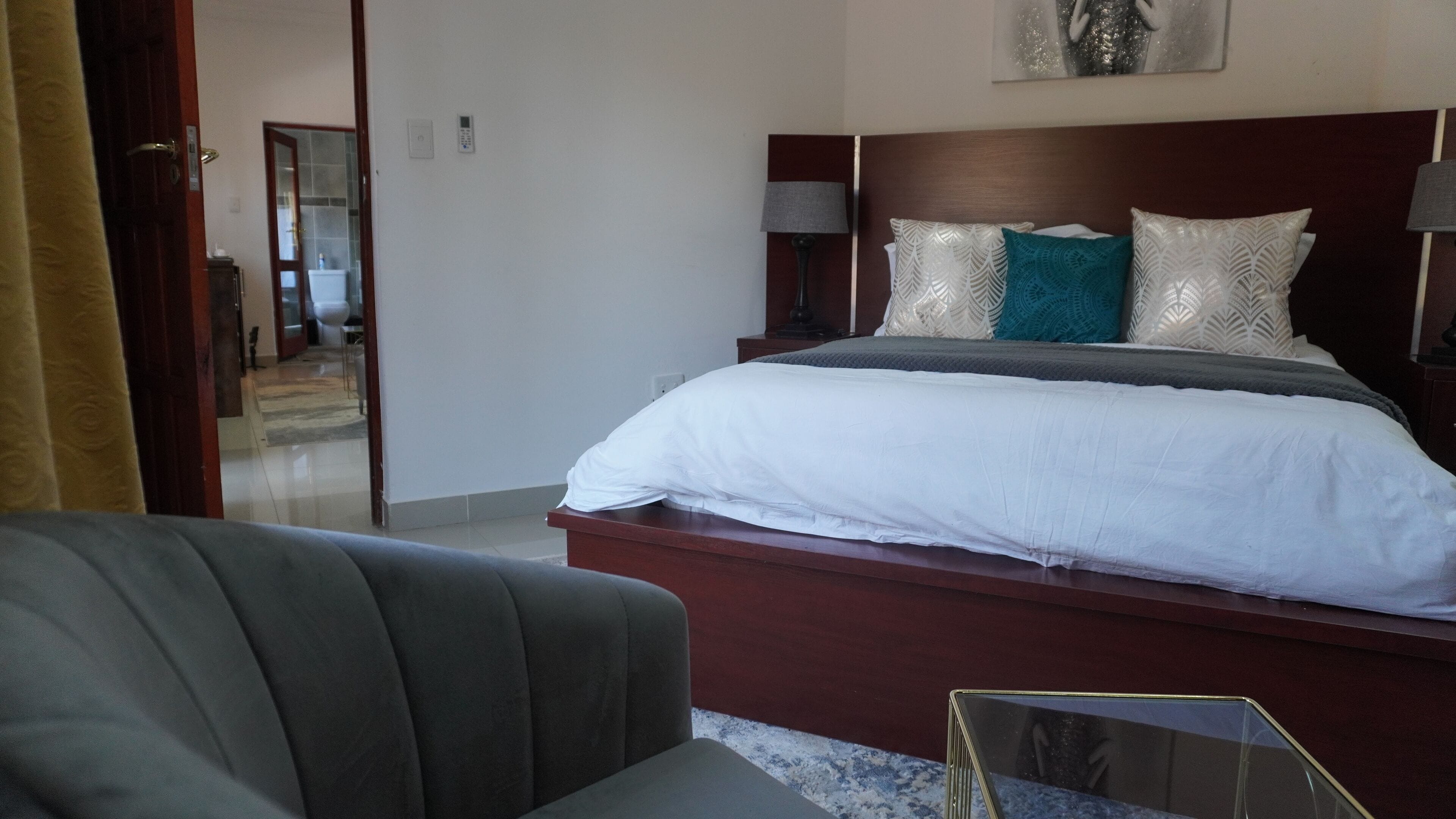 Quarto de hotel com uma cama, duas luminárias de cabeceira, uma mesinha de cabeceira e uma cadeira.