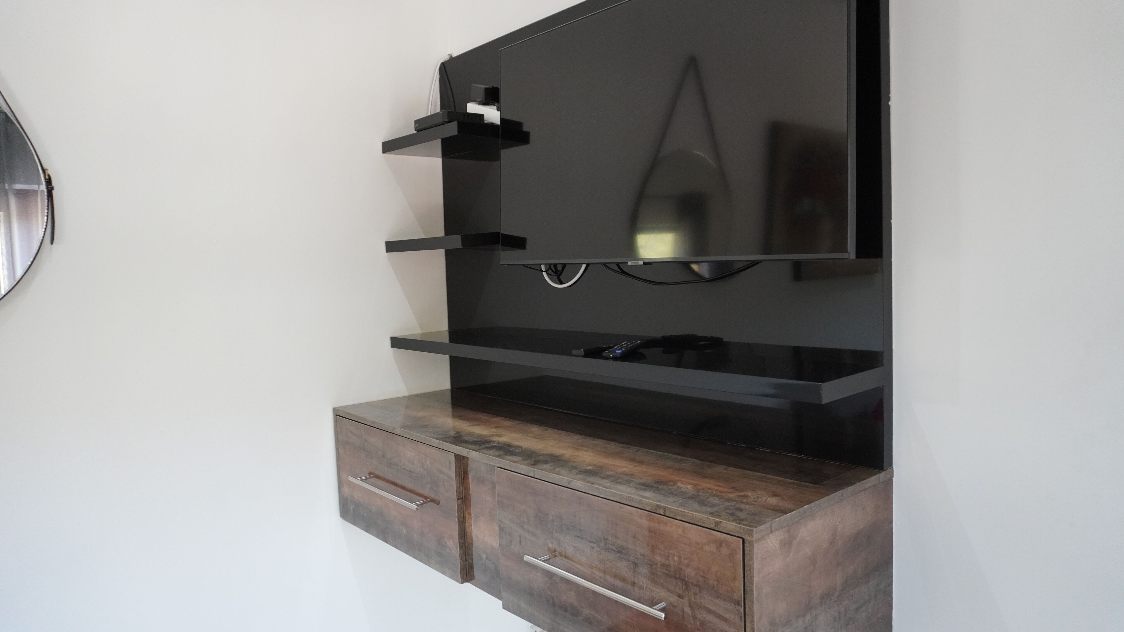 Un televisor de pared con un mueble de madera debajo.