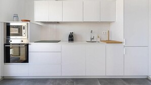 A modern kitchen with white cabinetry, a built-in oven, a coffee maker, and a sink. - Casa Alianto       . (El Pozo de los Frailes)