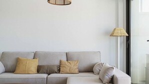 A modern living room with a grey sofa, a wooden coffee table, and a wicker lamp. - Casa Alianto       . (El Pozo de los Frailes)