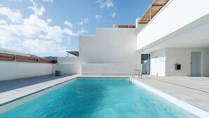 A modern outdoor swimming pool with a clear blue pool, surrounded by a white building with a wooden deck and a door. - Casa Alianto       . (El Pozo de los Frailes)