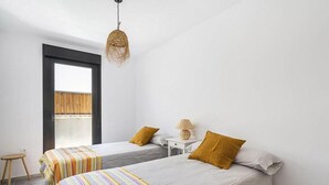 A modern bedroom with two beds, a small table, and a hanging light fixture. - Casa Alianto       . (El Pozo de los Frailes)