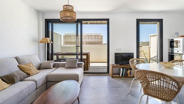 A modern living room with a sofa, a dining table, wicker chairs, a TV, and a bookshelf. - Casa Alianto       . (El Pozo de los Frailes)