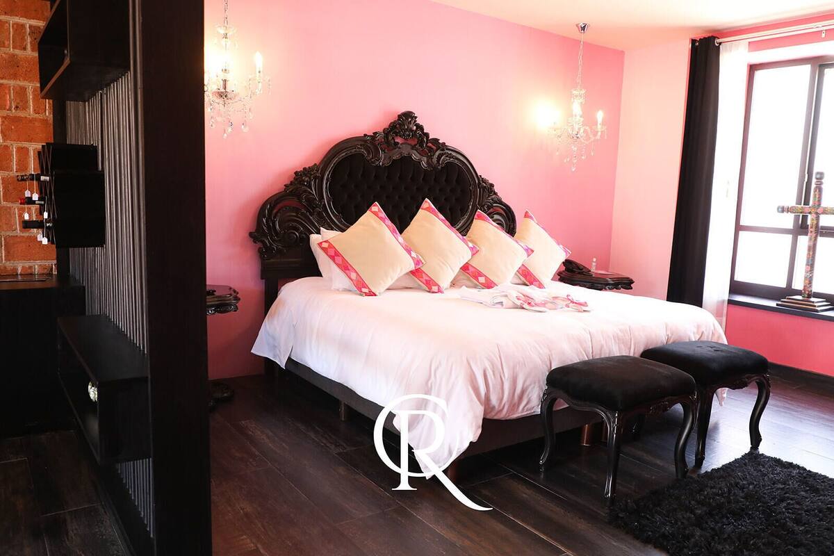 Ein Schlafzimmer mit einem großen Bett, einem Holz-Kopfteil und einer schwarzen Bank.