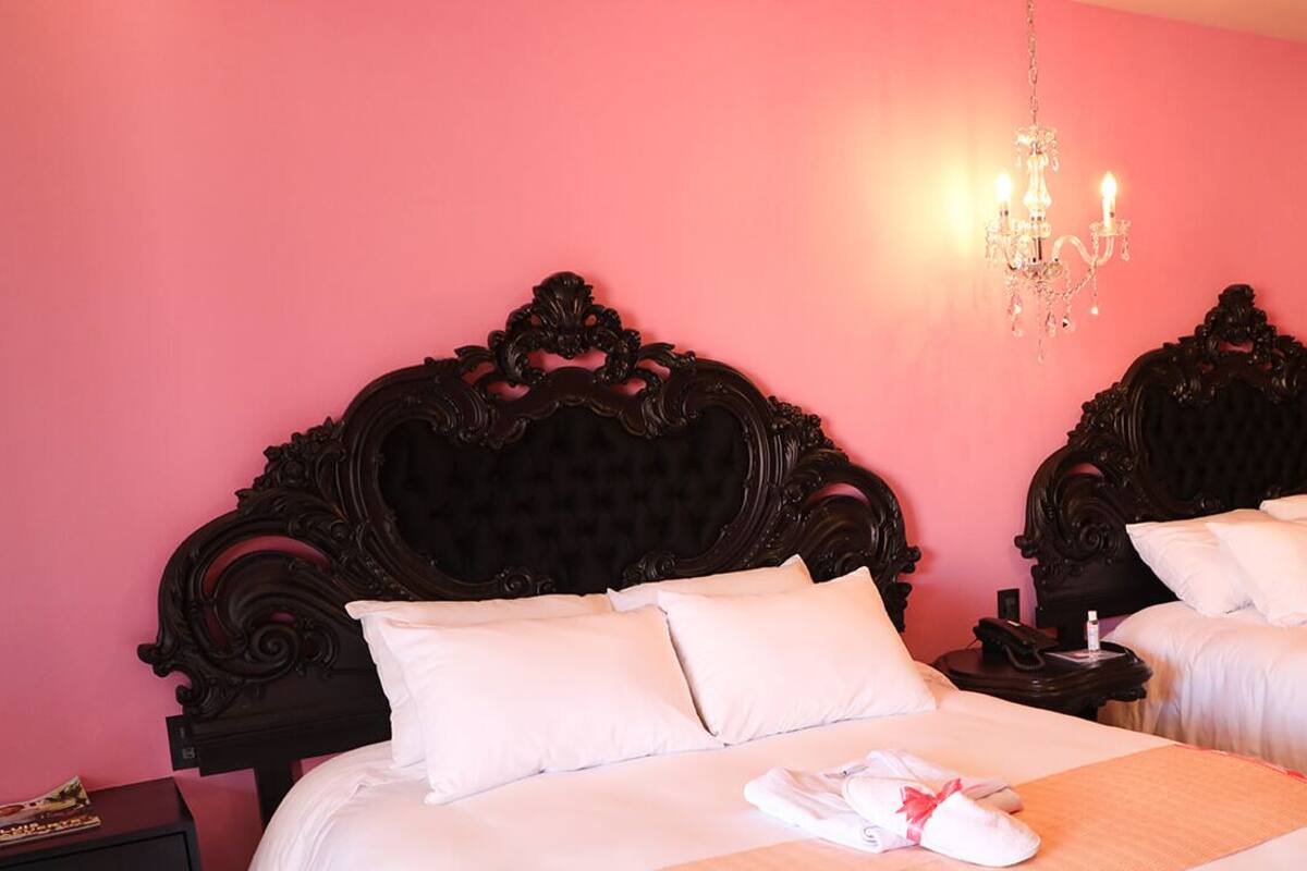 Ein Hotelzimmer mit zwei Betten, jeweils mit aufwendigen Holzkopfteilen und weißer Bettwäsche.
