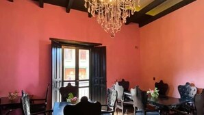 A dining area with a chandelier, wooden chairs, and a table.