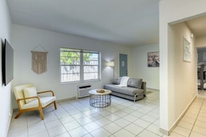 A modern living room with a sofa, a chair, a coffee table, and a large window.