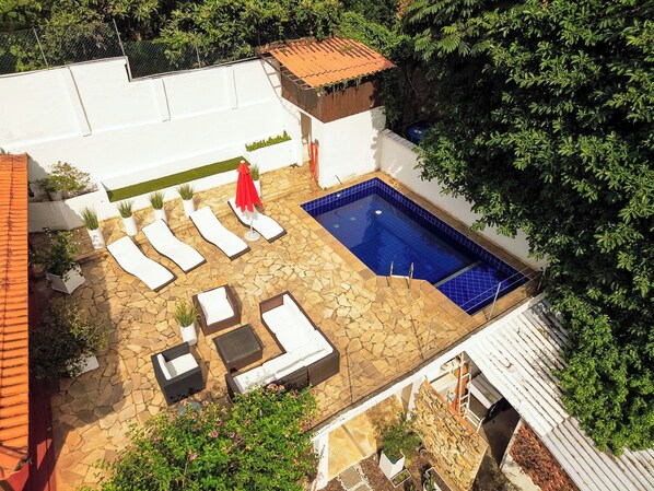 Una piscina en la azotea con sillones de descanso y plantas en macetas.