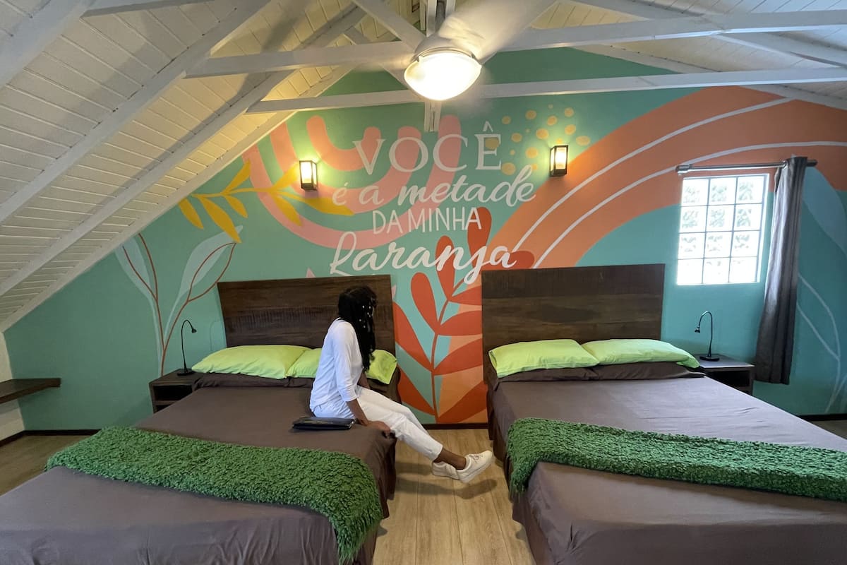 A room with two beds, a mural with text, and a window.