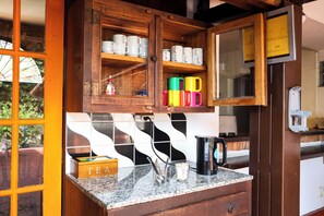 Una cocina con armarios de madera, salpicadero de azulejos y encimera con una caja de té y utensilios.