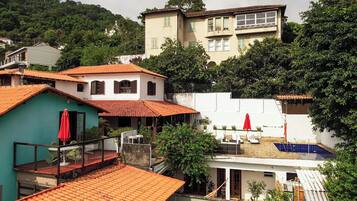Zona residencial com vários edifícios, uma piscina e uma varanda com um guarda-sol vermelho.