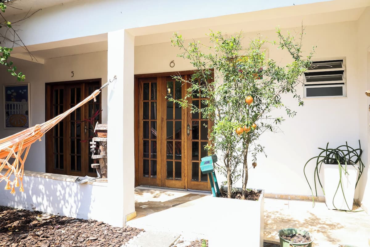 A building with a wooden door, a hammock, and a potted plant.