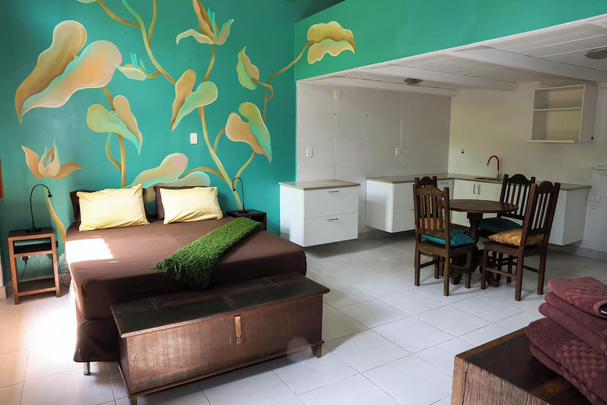 A bedroom with a bed, bedside table, and a wall mural.