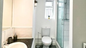 Un baño pequeño con lavamanos, inodoro y cabina de ducha de vidrio.