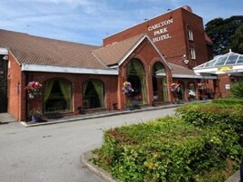 A red-brick Carlton Park Hotel with arched windows and a sign above the entrance.