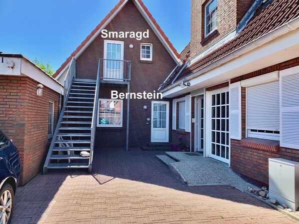 Une maison à deux étages, construite en briques, avec un escalier menant à l’étage supérieur, un garage et une véranda couverte.
