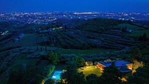 Una casa grande con piscina, rodeada de exuberante vegetación y campos en terrazas.