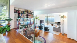 Un espacio habitable amplio con una gran estantería, una mesa de comedor y vistas a la ciudad.