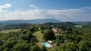 Un vaste domaine doté d’une piscine, entouré d’une végétation luxuriante, et comprenant un bâtiment en pierre.