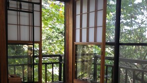 Een traditionele Japanse kamer met tatami vloeren, schuifdeuren van shoji-papier en uitzicht op een weelderige tuin.