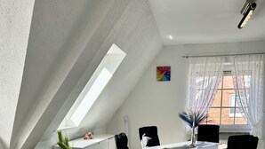A modern kitchen with a white countertop, black chairs, and a dining table. - Apartment with a view of the dyke for up to 4 people. -Turquoise (Büsum)