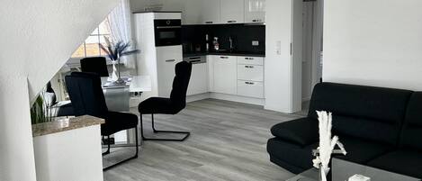 Enjoy a spacious living area with a sleek sofa and console table, complemented by a modern kitchen with contemporary appliances.