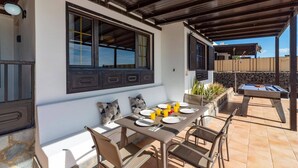 Eine Terrasse im Freien mit Esstisch für vier Personen, einem Billardtisch und einer Steinsäule.