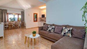 Ein Wohnzimmer mit einer Couch, einem kleinen Tisch und einem Essbereich mit Stühlen und einem Tisch.