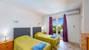 A hotel room with two beds, a wooden dresser, and an air conditioning unit. - Villa Mi Sueno by Villa Plus (La Capellania)