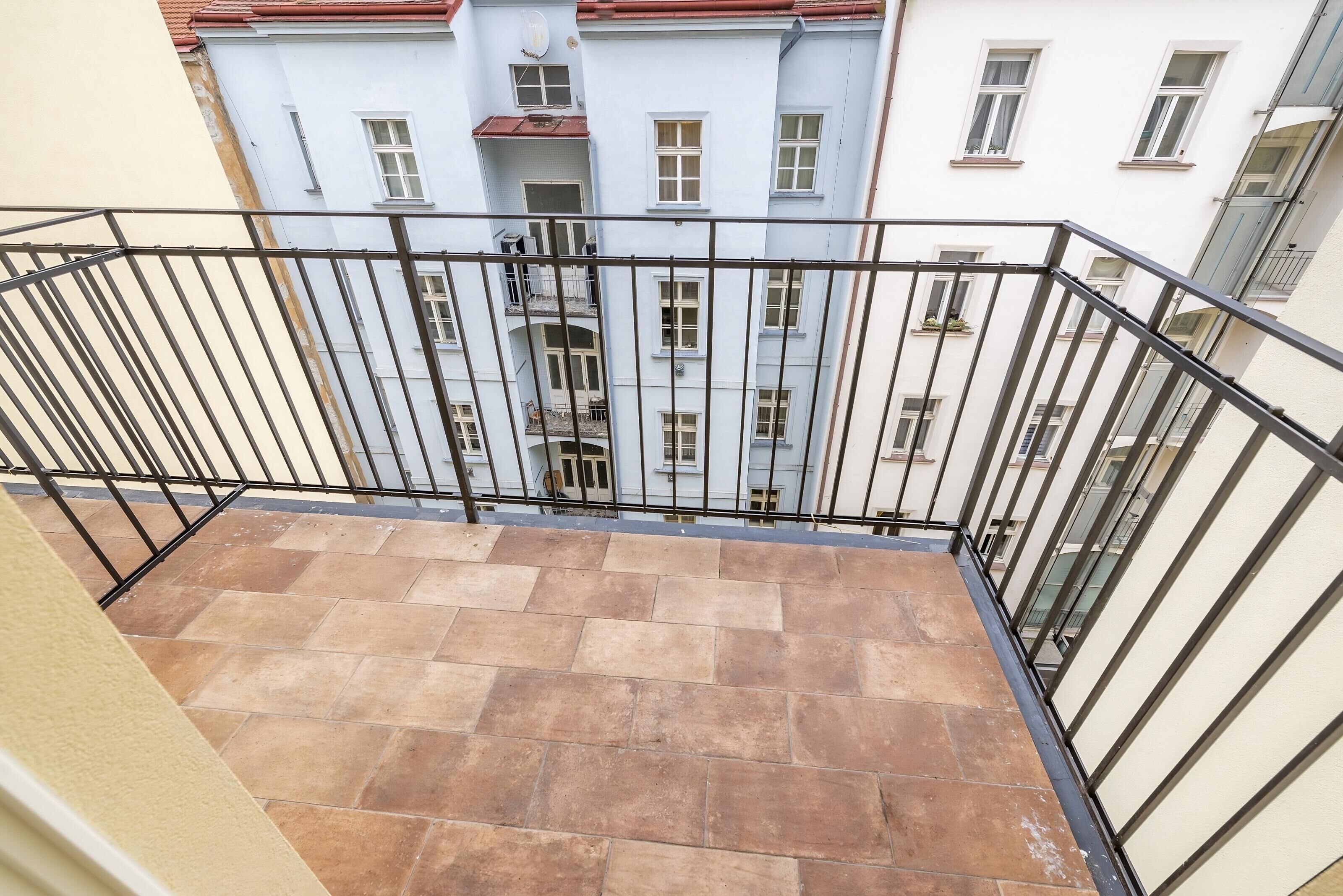 A balcony with a tiled floor and a metal railing.