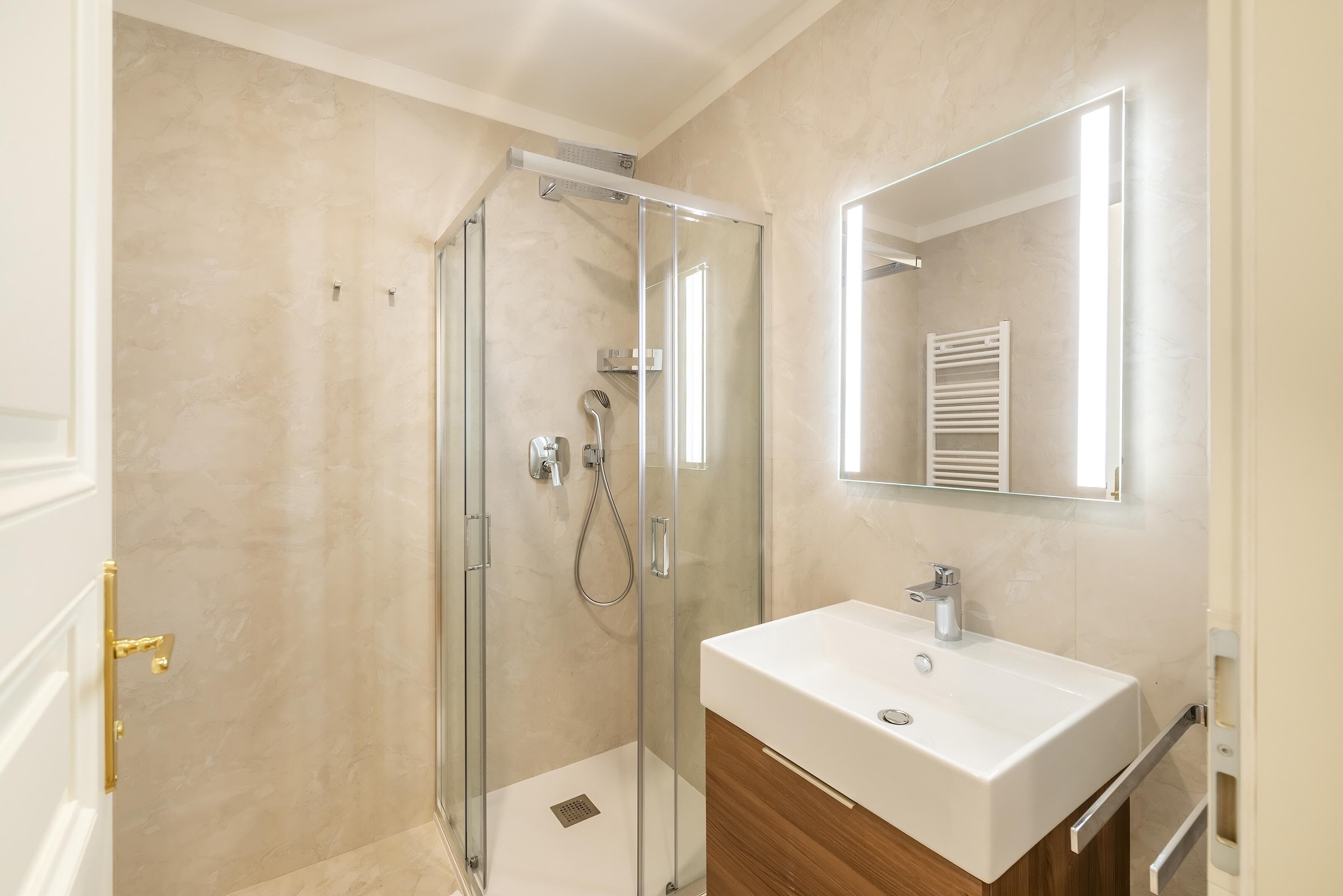 A modern bathroom with a glass-enclosed shower, a white sink, and a mirror above it.
