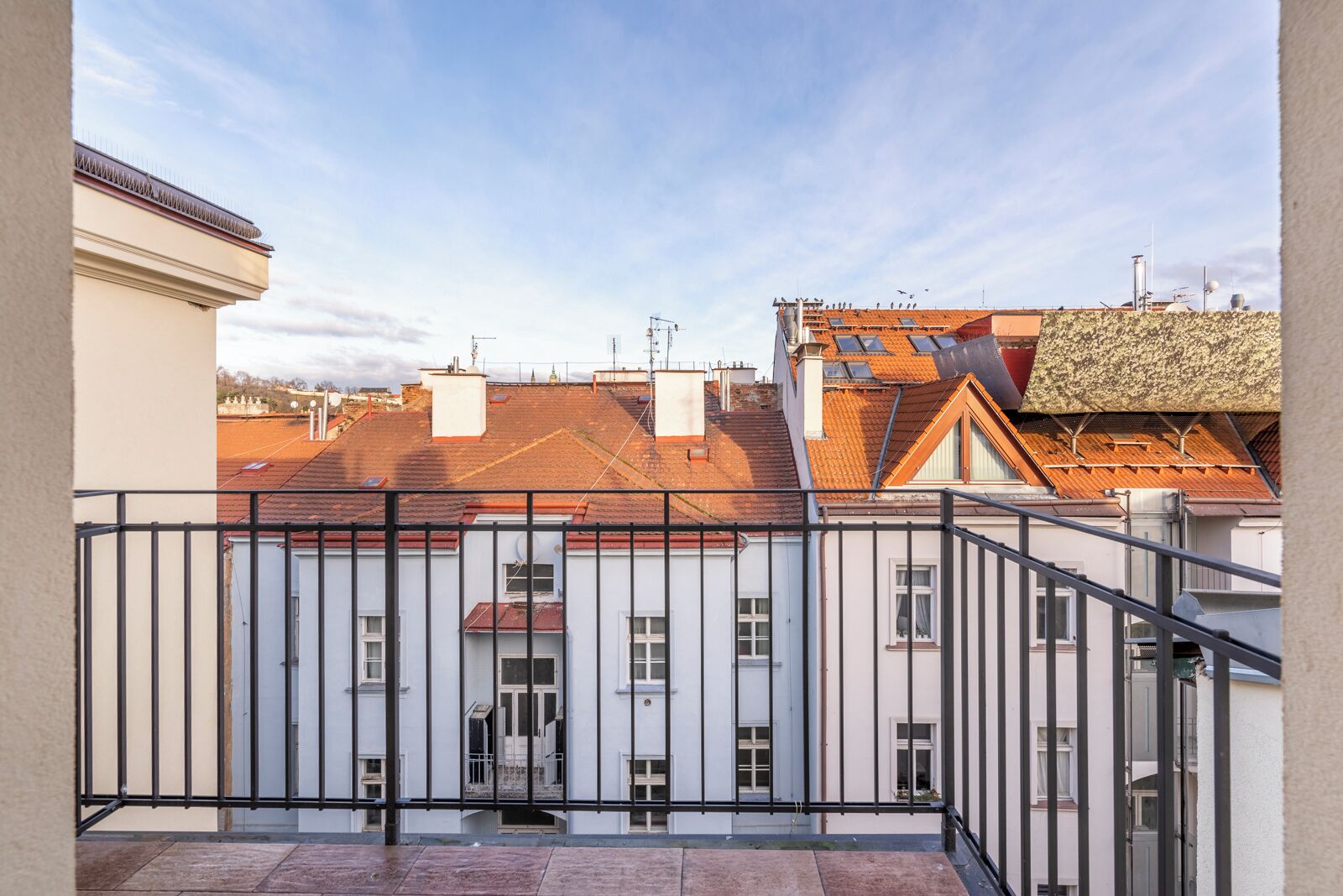 Un immeuble résidentiel doté d’un balcon, d’un escalier et offrant une vue sur les bâtiments voisins.