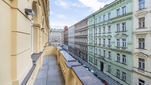 A narrow alleyway between buildings with balconies, featuring classical architecture and a clear sky. - Petrin Tower Residence (Prague)