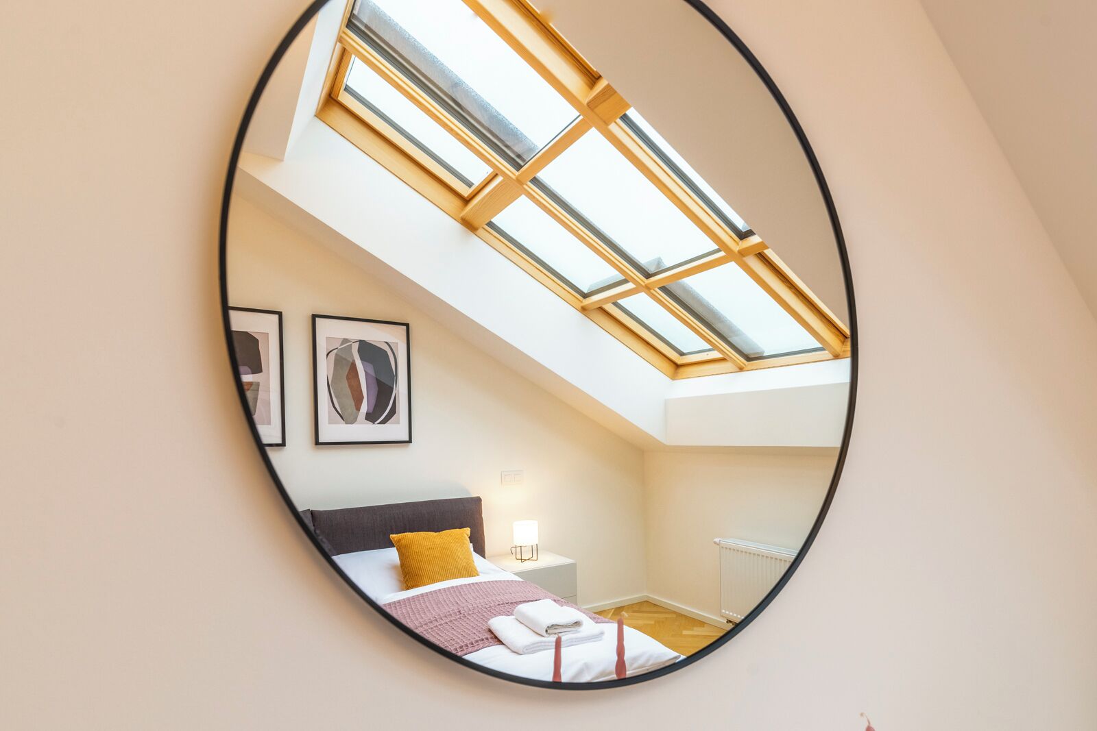Ein Schlafzimmer mit Dachfenster, einem Bett, einem Nachttisch und zwei gerahmten Bildern an der Wand.