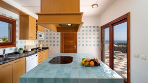 Una cocina con una isla central, microondas y vistas al balcón.